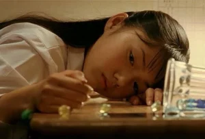 机にうつ伏せになり、けだるげな視線を送る制服姿の宮崎あおい(映画『害虫』より)