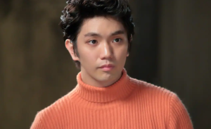 「オレンジ色のタートルネックセーターを着用し、真剣な表情で見つめるAぇ! groupの正門良規。黒髪にボリュームを持たせたスタイリング。