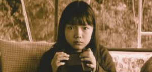 双眼鏡のような黒い箱型の道具を両手で持ち、まっすぐ前を見つめる少女時代の宮崎あおいさん(映画『EUREKA ユリイカ』より)