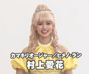 『王様戦隊キングオージャー』の劇中衣装で、金髪のウィッグとティアラを身につけ、女王としての気品に溢れる笑顔を見せる村上愛花。黄色いドレスが彼女の華やかさを引き立てている。