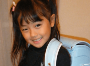 水色のランドセルを背負って笑顔を見せる、小学生時代の上坂樹里