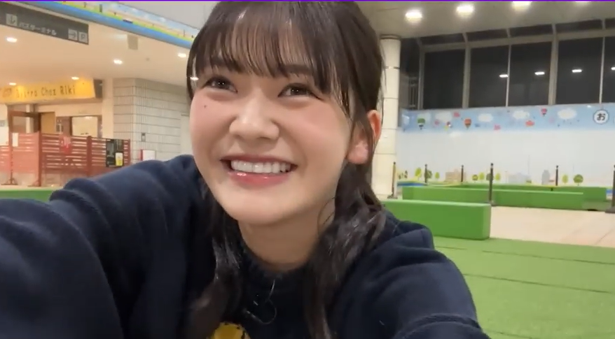 カメラに向かって満面の笑みを見せる乃木坂46・5期生の奥田いろは。夜の屋外広場を背景にした自撮り風のオフショット。