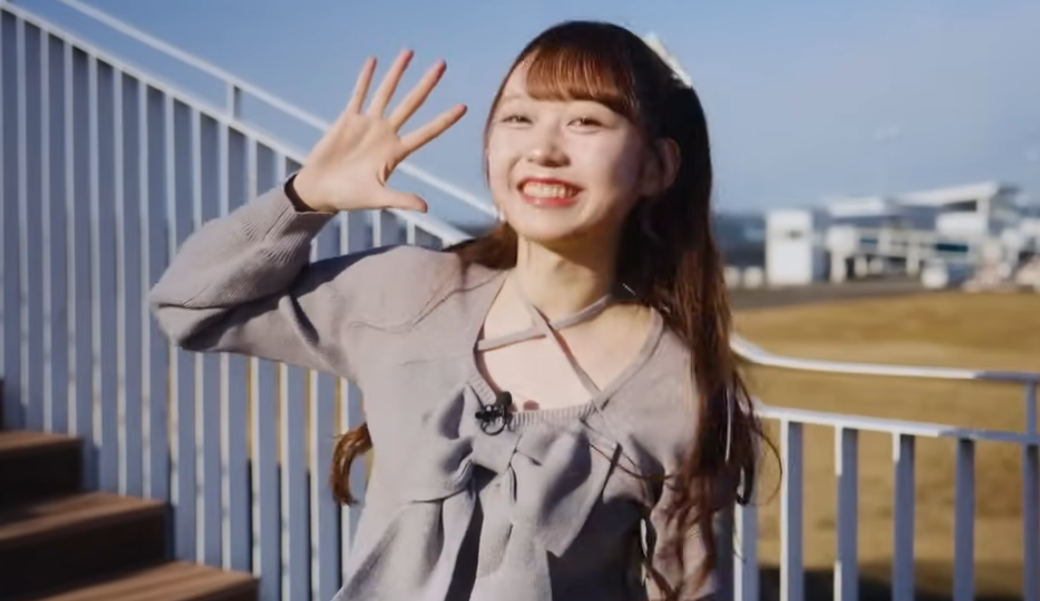 青空の下、屋外の階段でカメラに向かって大きく手を振り、屈託のない笑顔を見せる大盛真歩。地元・茨城県でのロケ中の一コマと思われ、アイドルとしての華やかさと、故郷で見せる親しみやすい素顔が同居した瞬