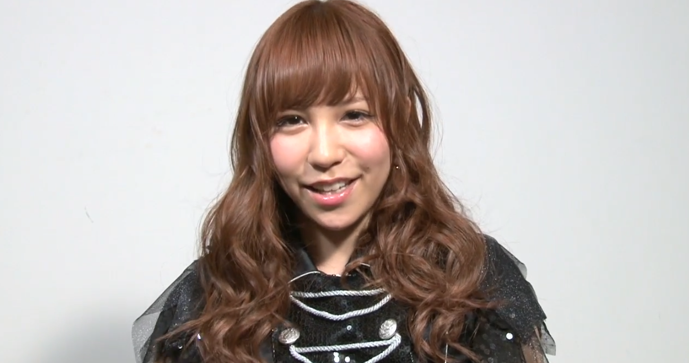 黒いステージ衣装を着て笑顔を見せるアイドル時代の河西智美