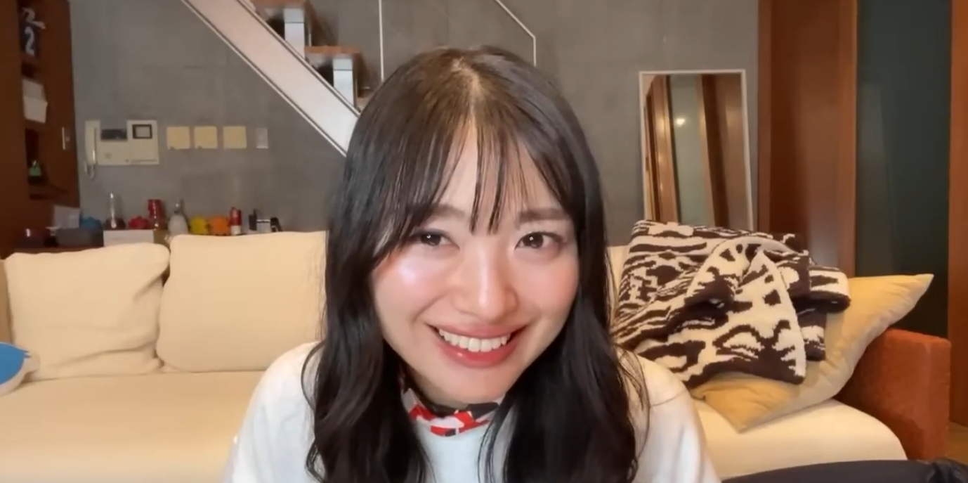 現在の北原里英さん。白いトップスを着て、自宅のリビングのようなリラックスした空間でカメラに向かって笑顔を見せる様子