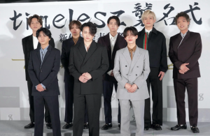 timelesz 襲名式」と書かれた横断幕を背景に、スーツ姿で整列する8人の男性グループ(timelesz)の集合写真。