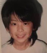少し長めの黒髪でカメラを見つめ、はにかんだように微笑む幼少期（小学生時代）の松島聡さんの顔写真