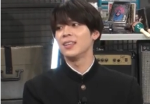 黒い詰襟学生服（学ラン）を着用して優しく微笑む、黒髪短髪の松島聡さんのテレビ出演時の姿